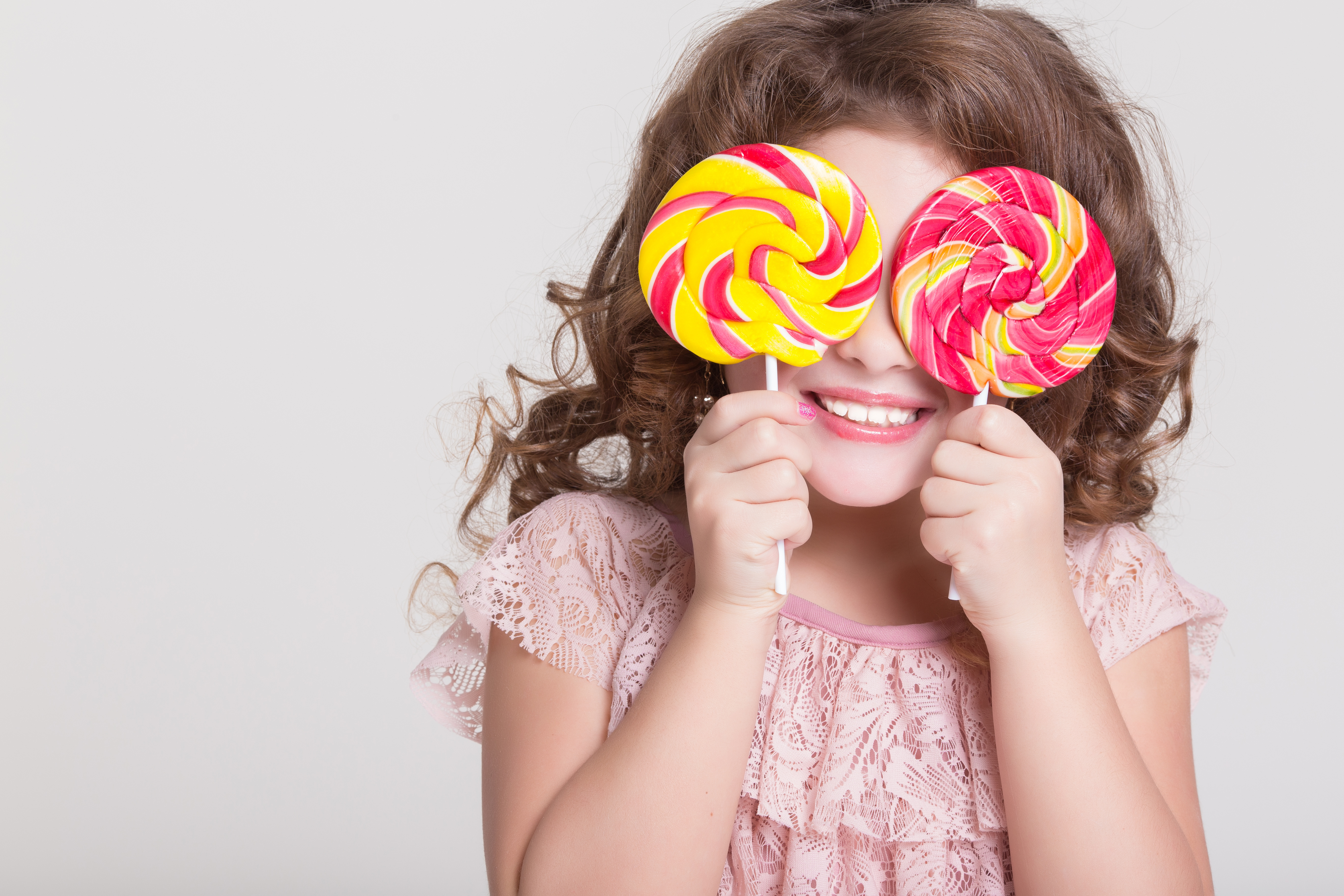 Young girl holding lollipops up to her eyes 