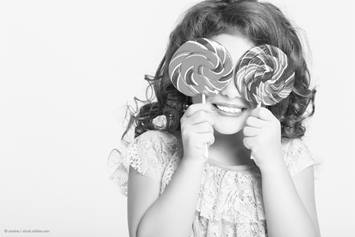 Young girl holding lollipops up to her eyes