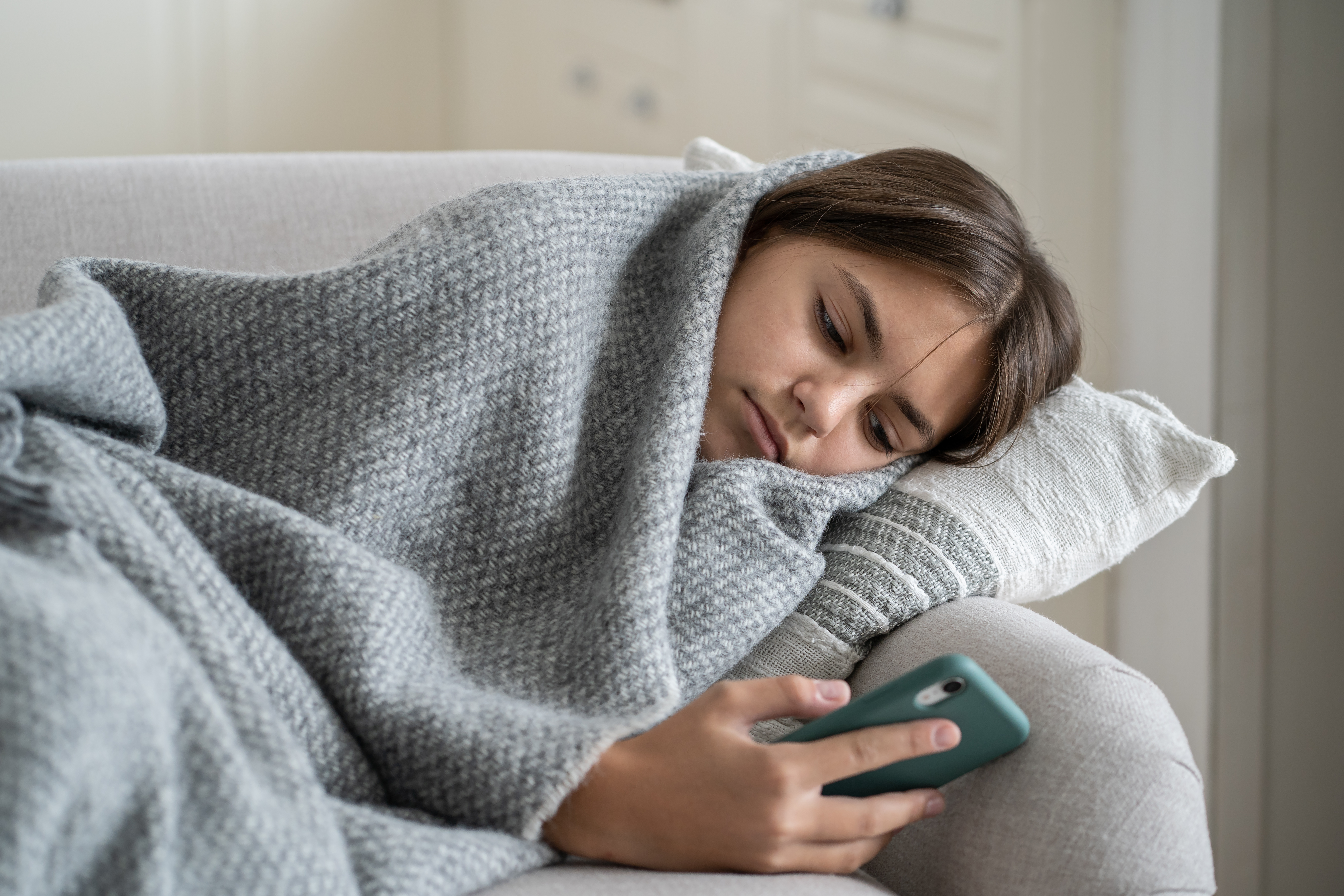 Young girl laying on the couch under a blanket