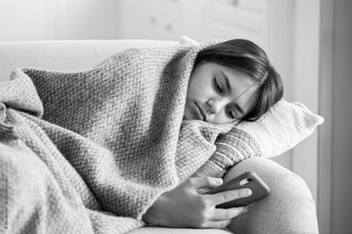 Young girl laying on the couch under a blanket