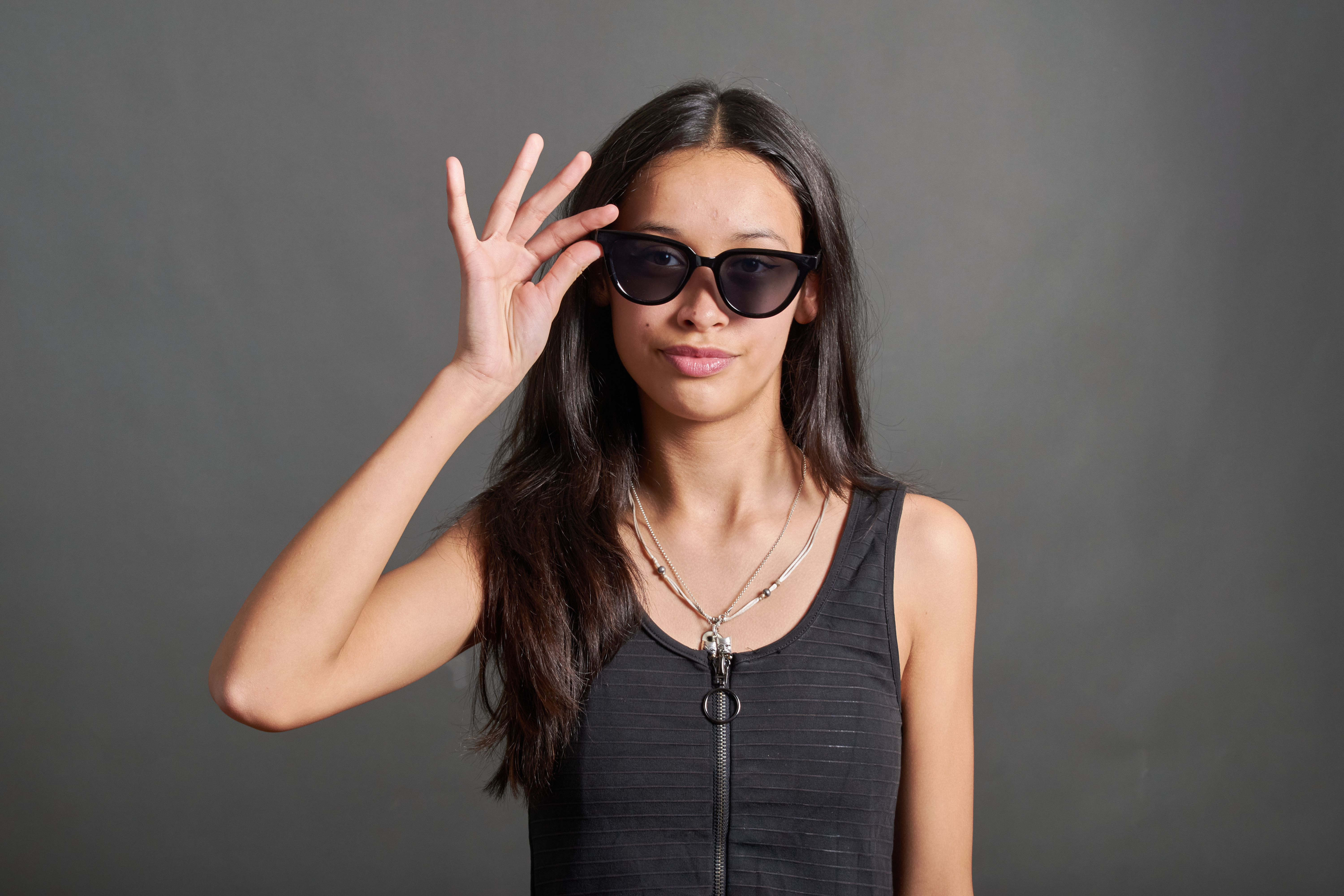 young woman touching her sunglasses with her right hand