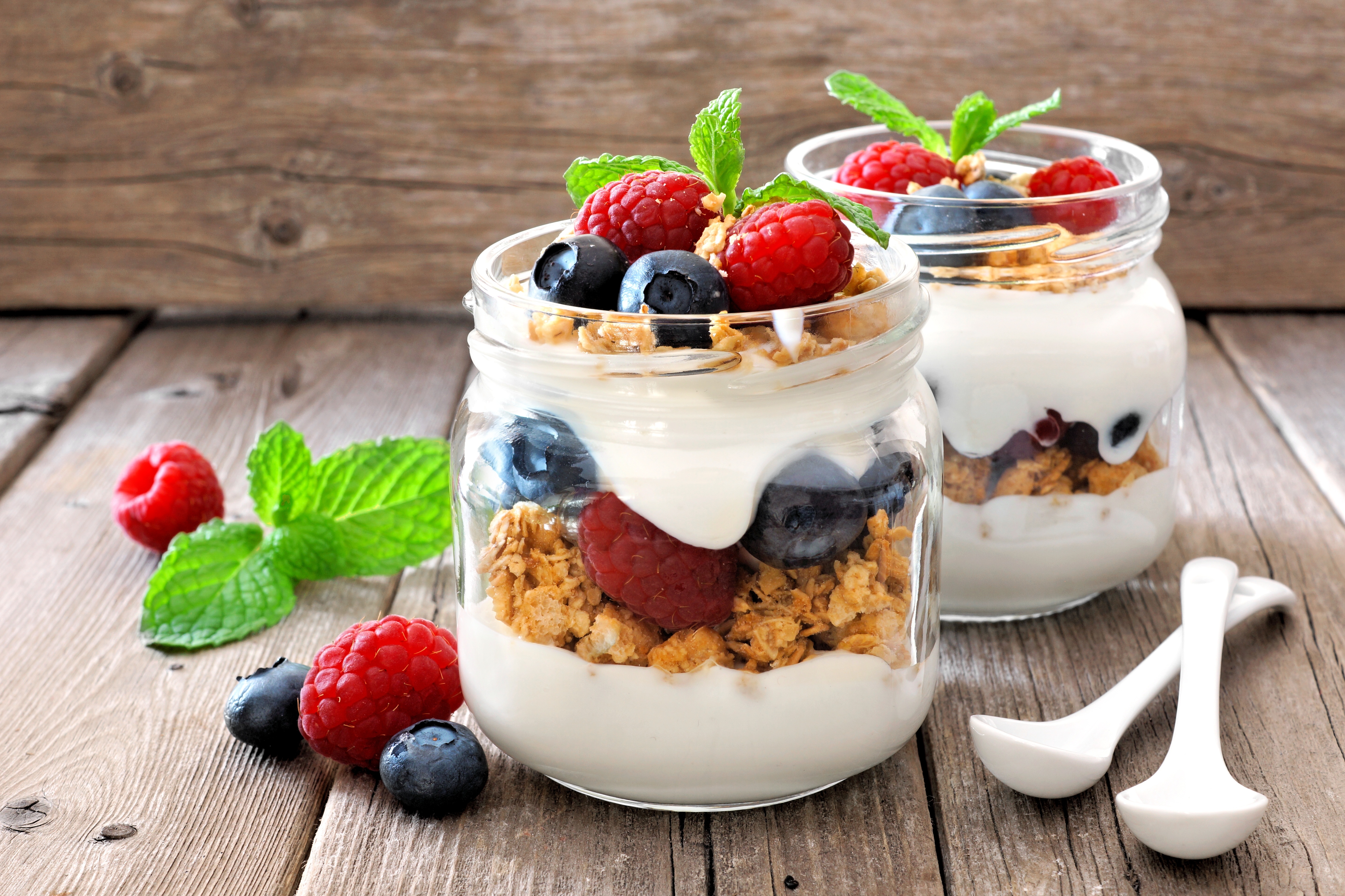 two yogurt parfaits sitting on a wooden table