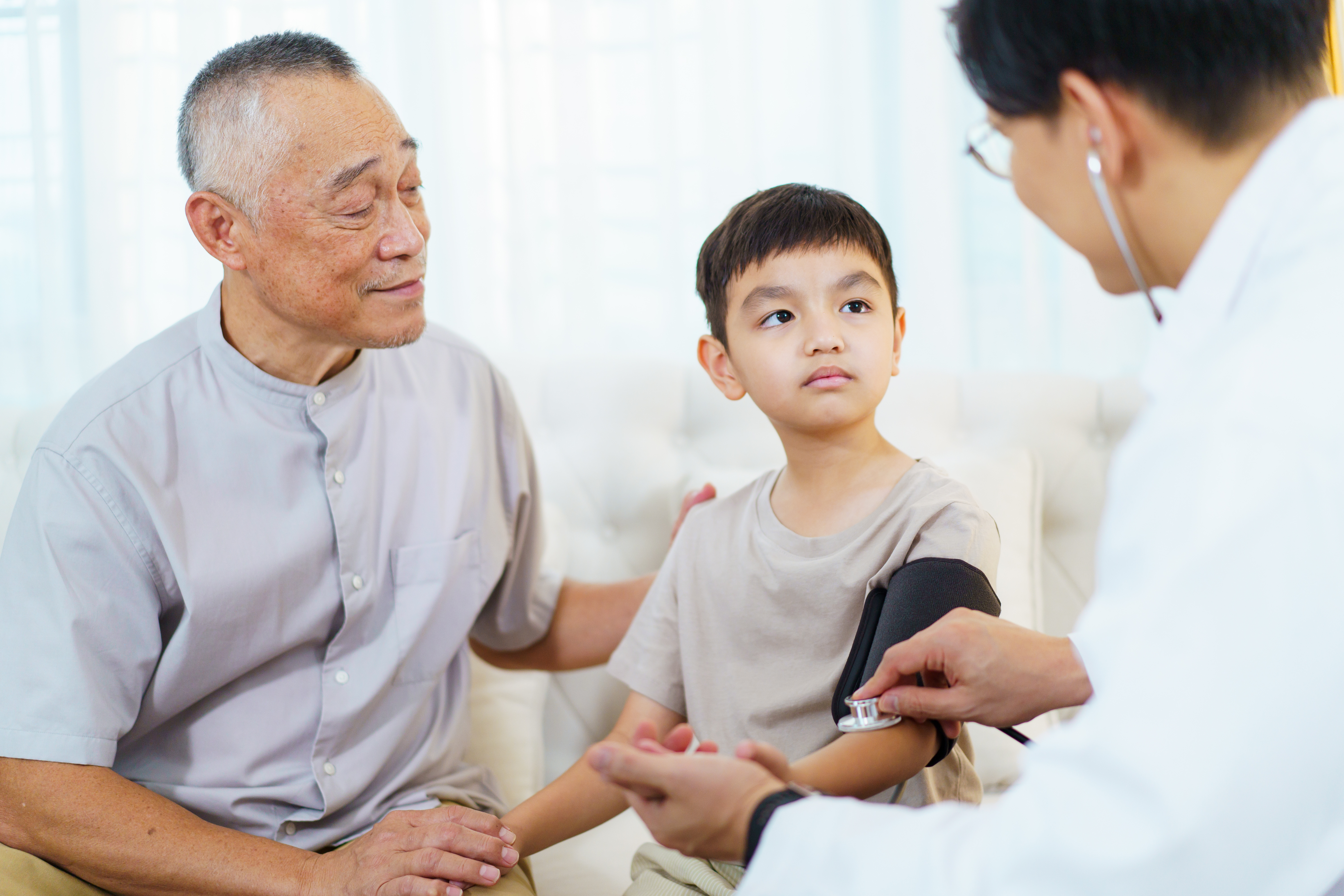 child getting his blood pressure taken, while holding his father's hand