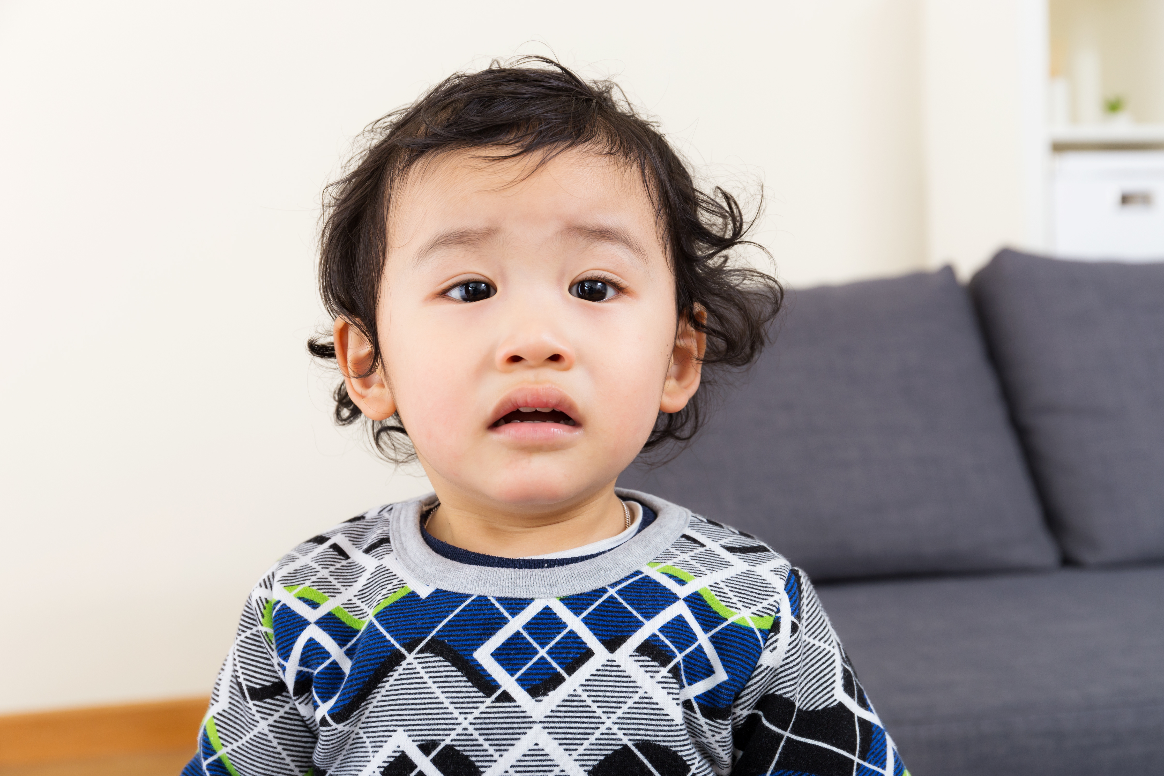 baby wearing a sweater looking like they might cry