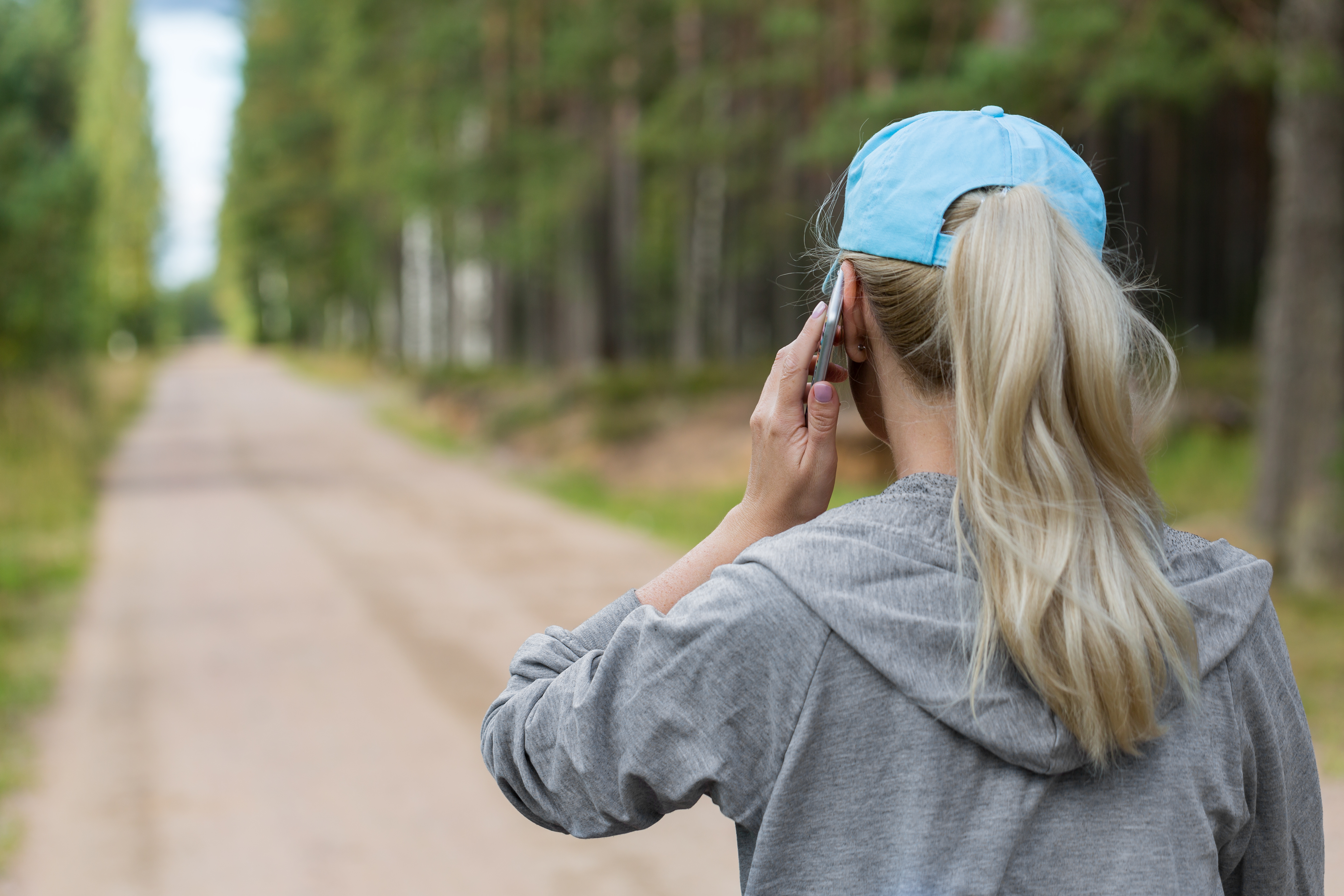 back of girls head with a ponytail and hat on the phone