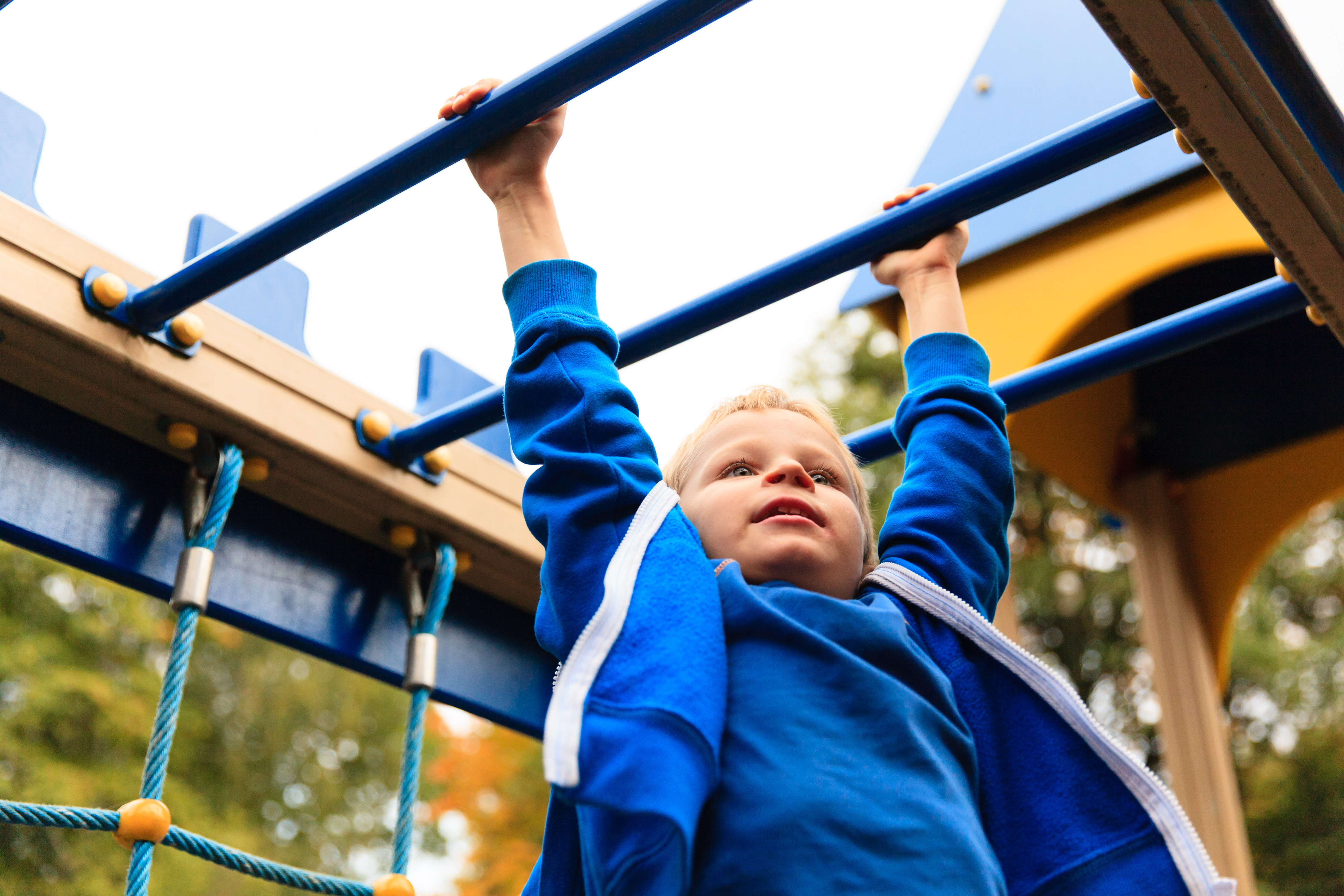 young boy hanging on the monkey bars