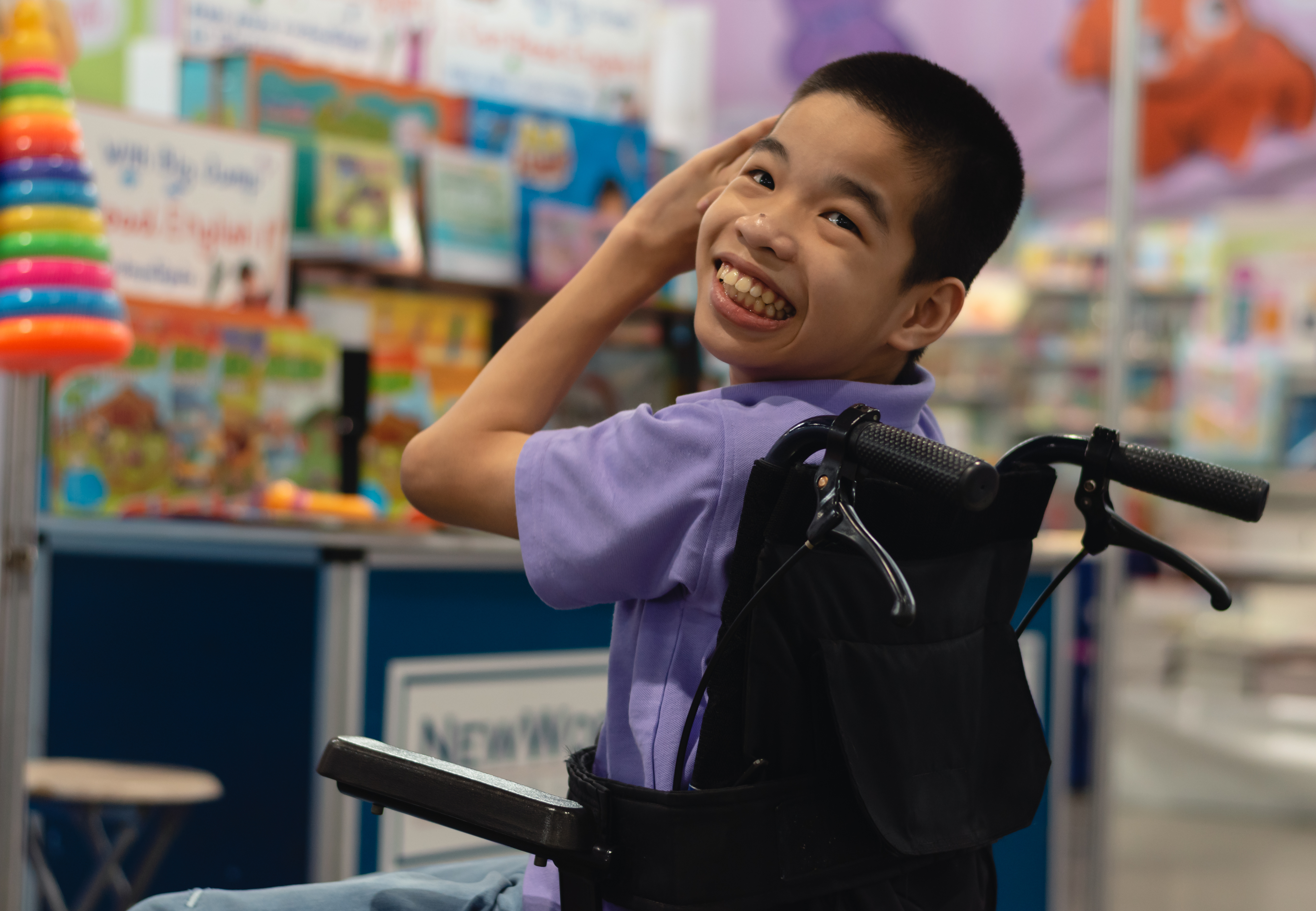 child in a wheelchair smiling at the camera