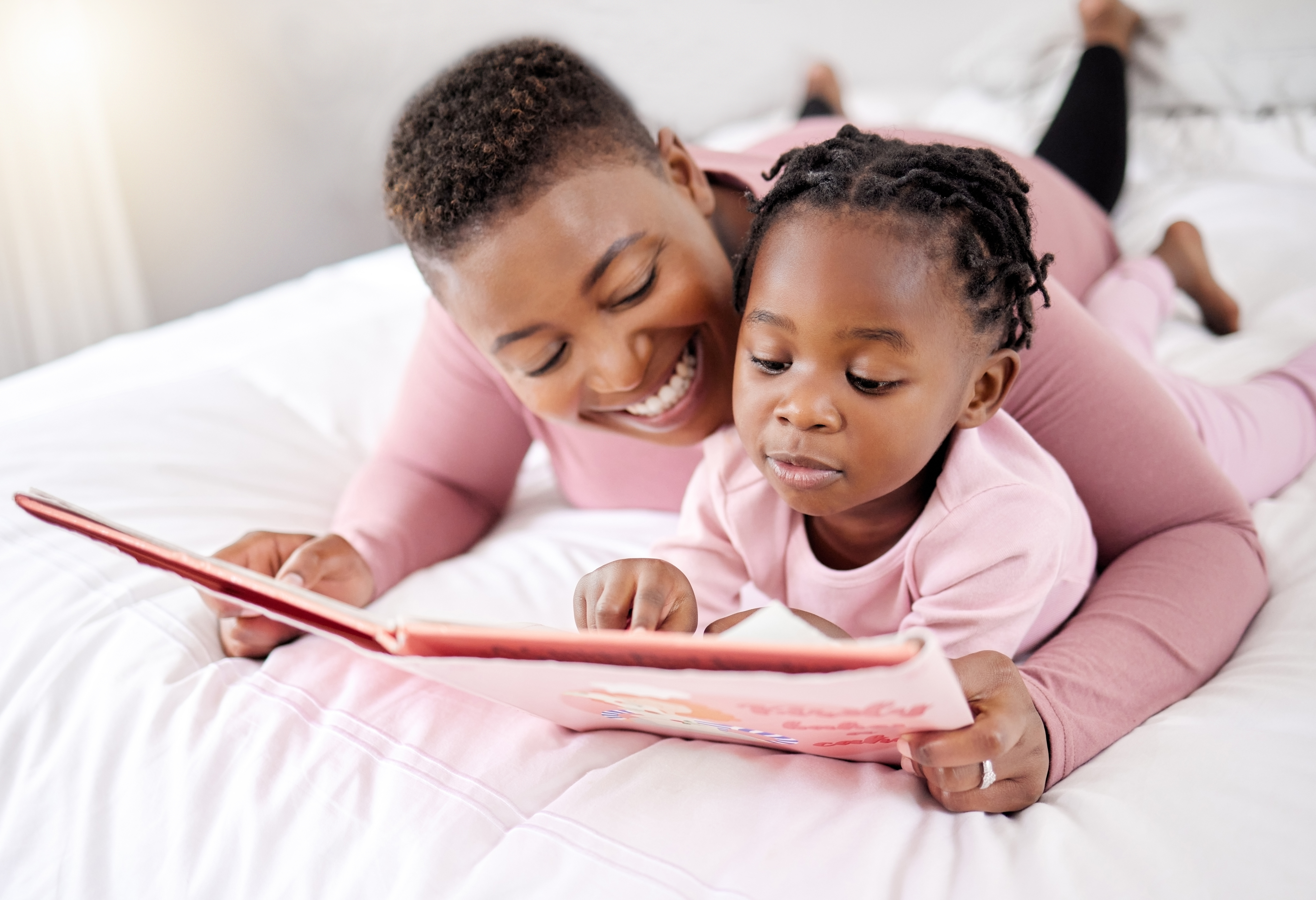 Mother reading a book to her child on a bed