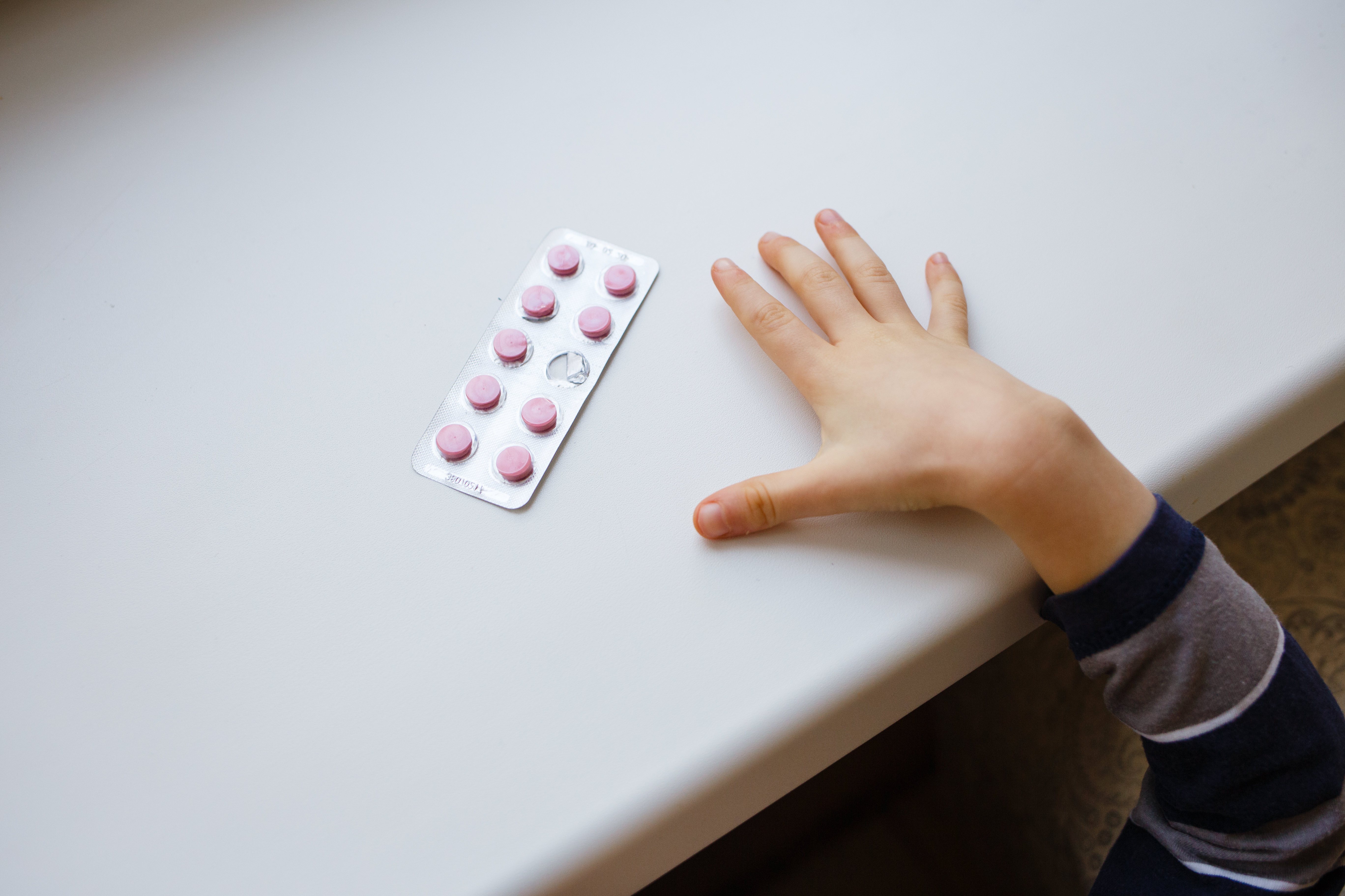 tablet of medications on a table with a little hand reaching for it
