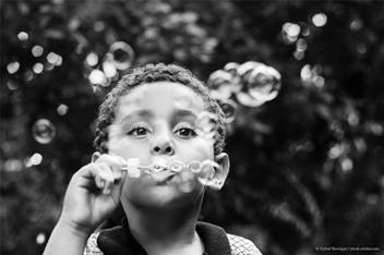 Elementary aged child blowing bubbles into the camera.