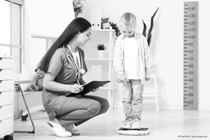 young child standing on a scale while a nurse is recording his weight beside him