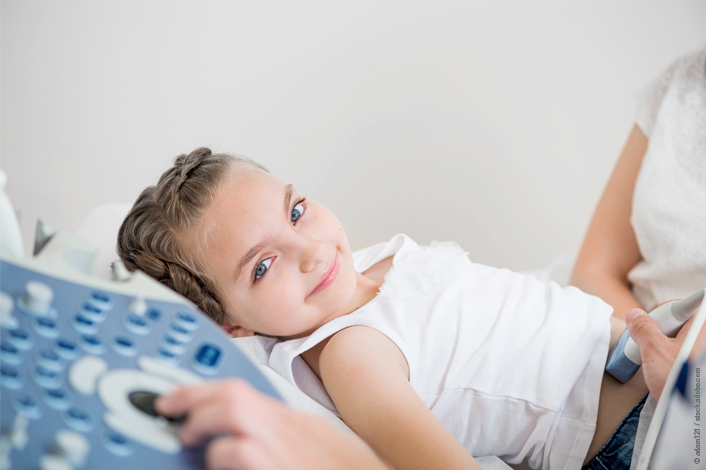 Photo of a child laying on an exam table getting a belly scan.