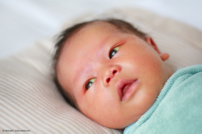 A close-up of a newborn baby lying on a soft blanket and wrapped in a light blue swaddle. The infant gazes upward with eyes open, highlighting an early stage of infancy and newborn health.