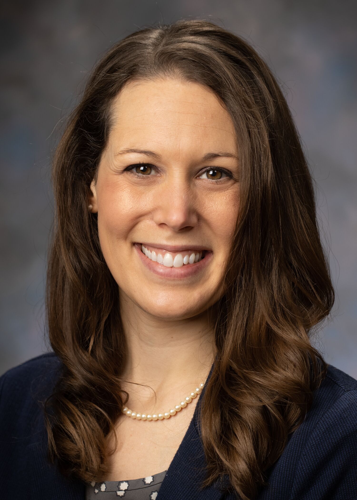Portrait of Allie DePoy, woman with long brown hair and a black shirt.