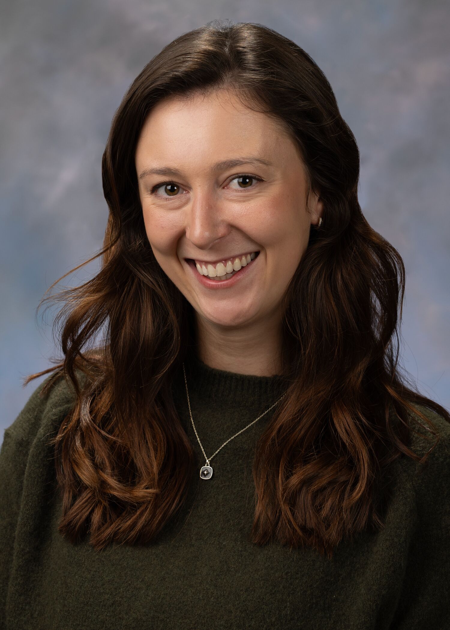 Portrait of Emily Stephan, woman with long brown hair and a green shirt.