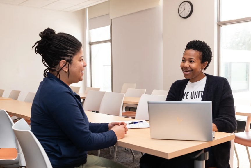 A smiling United Way volunteer chats with a client as they work on her taxes. They are seated with a laptop.