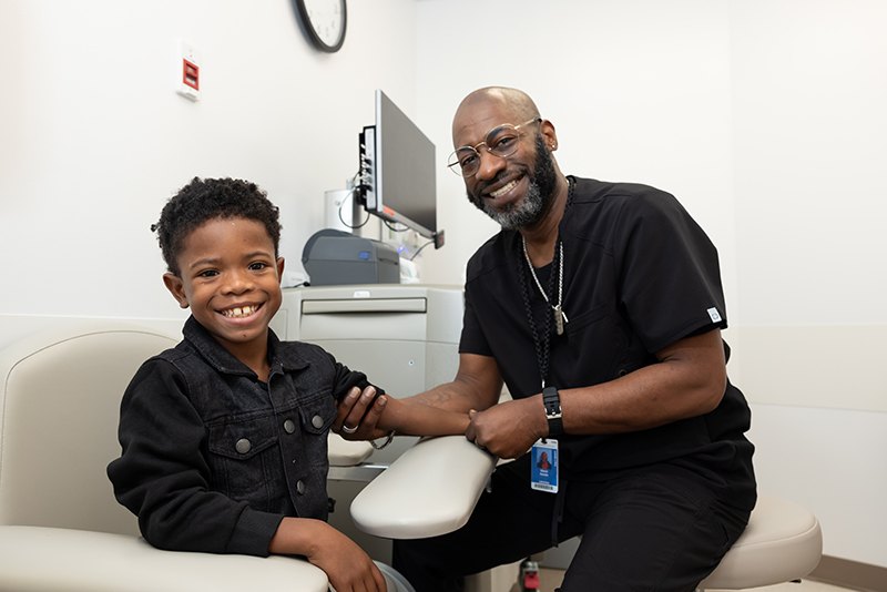 Smiling child with a healthcare professional during a clinic visit.