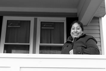 Alma is standing on her front porch, smiling