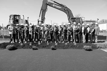 A group of individuals break ground at Lockbourne Greene. Construction equipment is visible behind them.