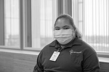 Project SEARCH participant, wearing a mask, standing near a wall of windows