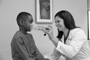 A health care provider assists an elementary aged child with a breathing treatment