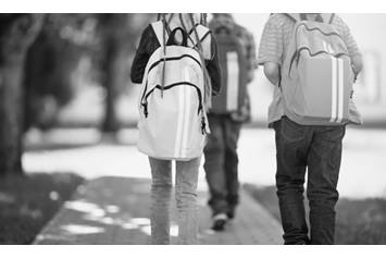 Three elementary aged kids walking down a path with back packs