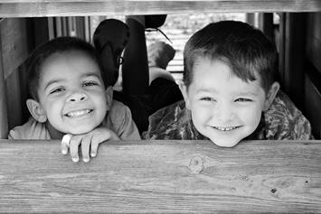 Two preschool aged boys, smiling, playing on a playground