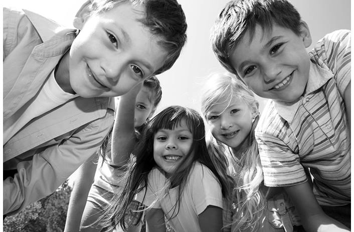 Group of smiling elementary aged kids leaning toward the camera