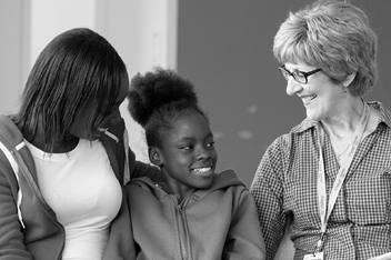 A PFK care coordinator is seated and is talking to a teen and an adult. All are smiling.