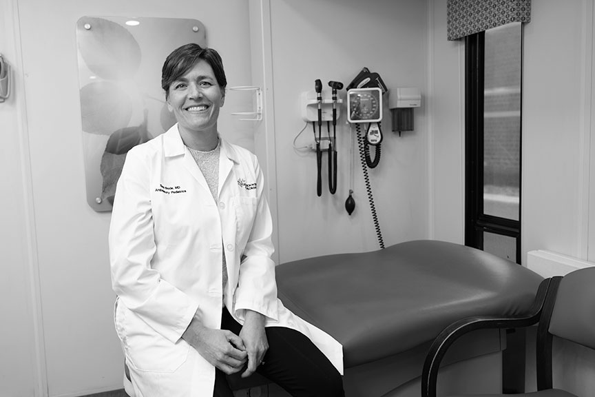 Dr. Bode is shown wearing a white coat, sitting in a mobile care center.