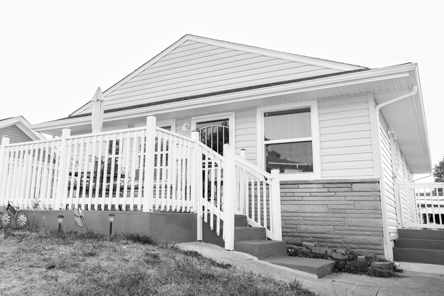 An exterior photo of a one-story home with a front porch and stairs.