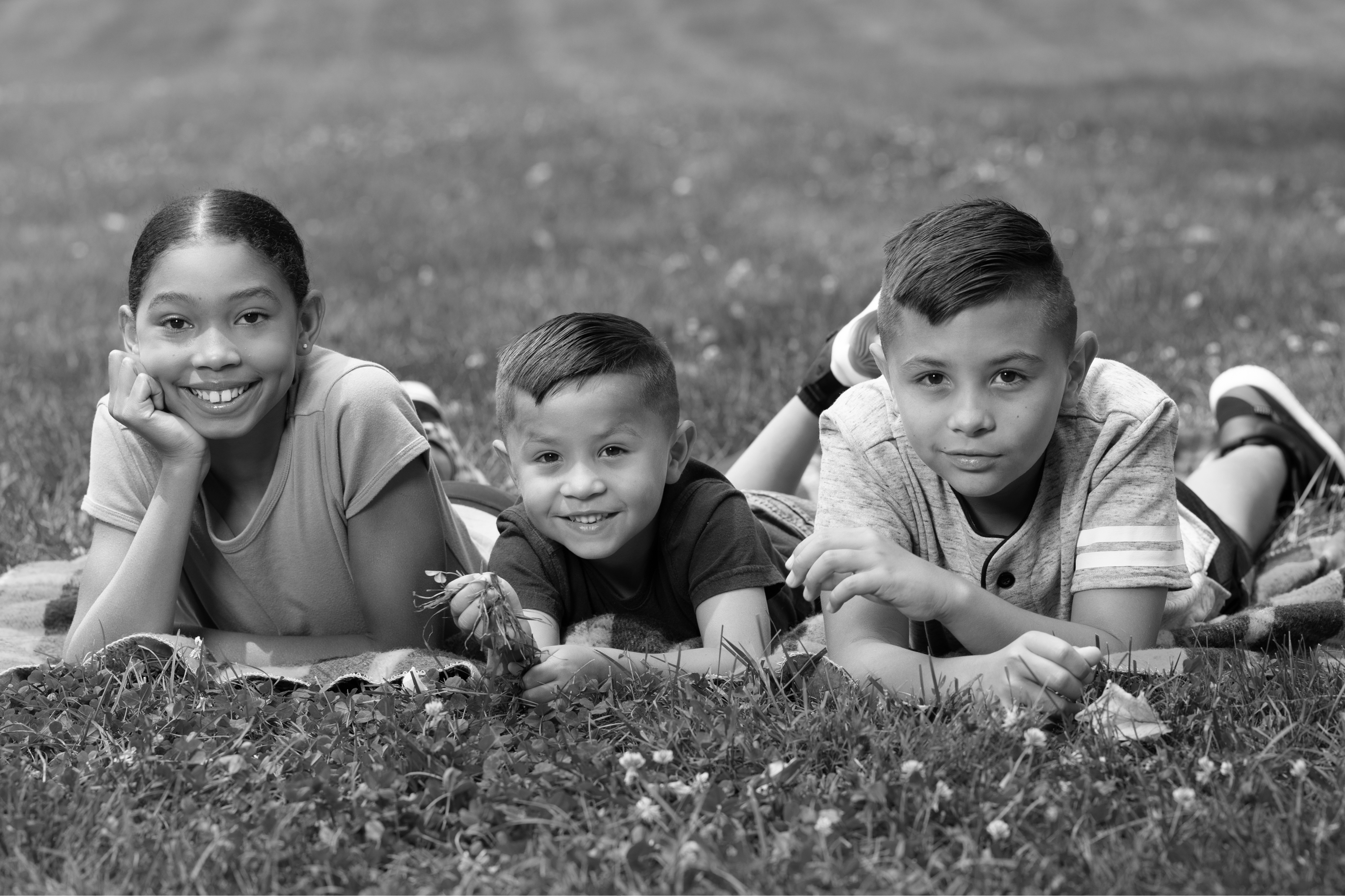 3 kids laying in grass