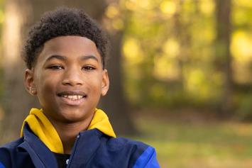 Smiling boy standing outdoors in a park setting