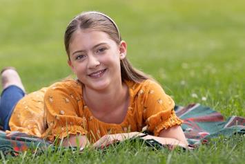 Girl lying on a blanket in a grassy park