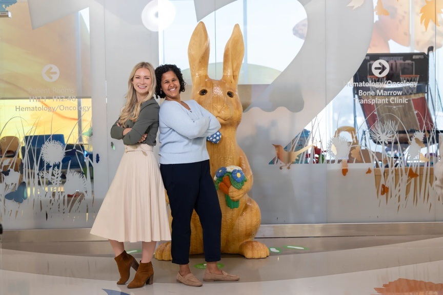 Two providers are standing back-to-back with their arms crossed while they smile at the camera.