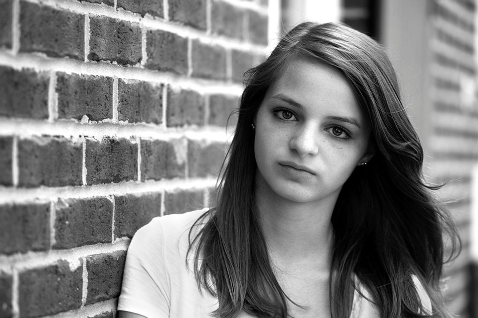 Teenage girl leaning against a brick wall