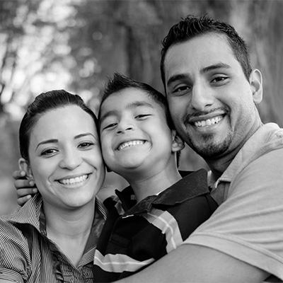 Family hugging and smiling in a park.