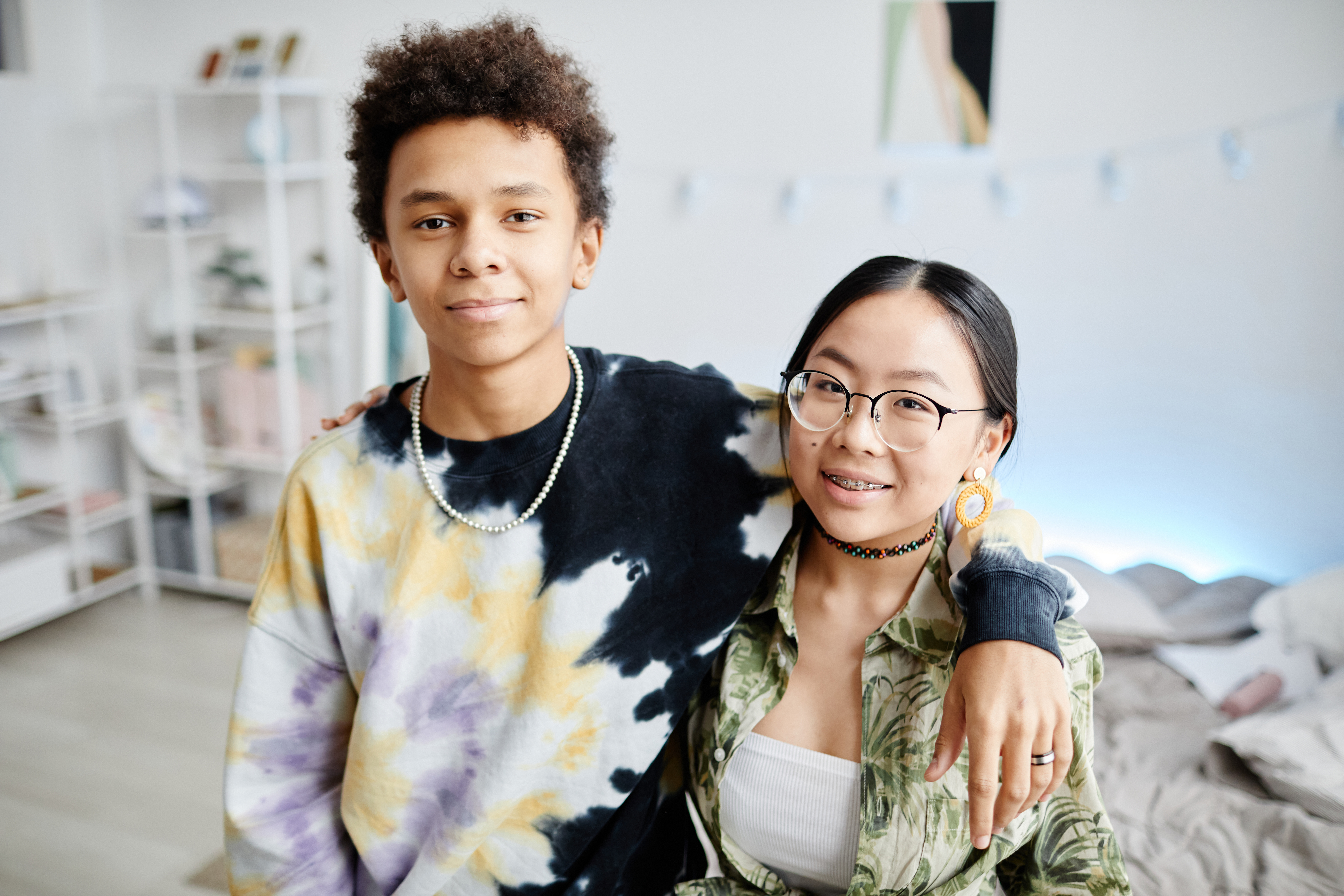 One male and one female teenager standing with their arms around each other.