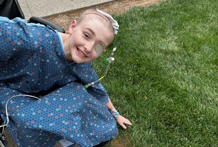 Aiden outside in a wheelchair touching grass