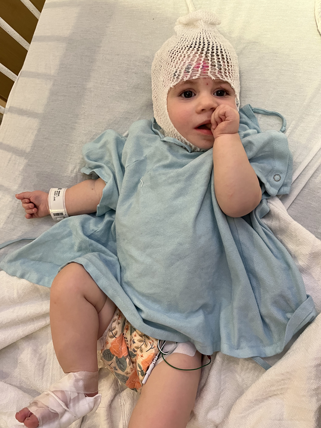 Baby in hospital gown sucking her thumb