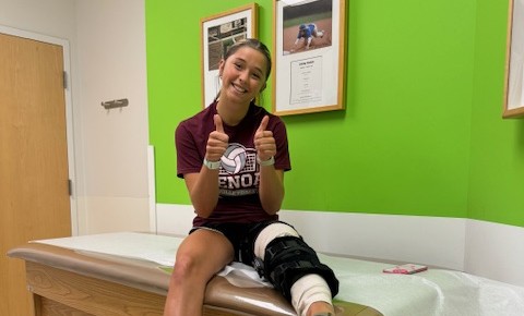 Izzy sitting on a Dr. bed with a knee brace on