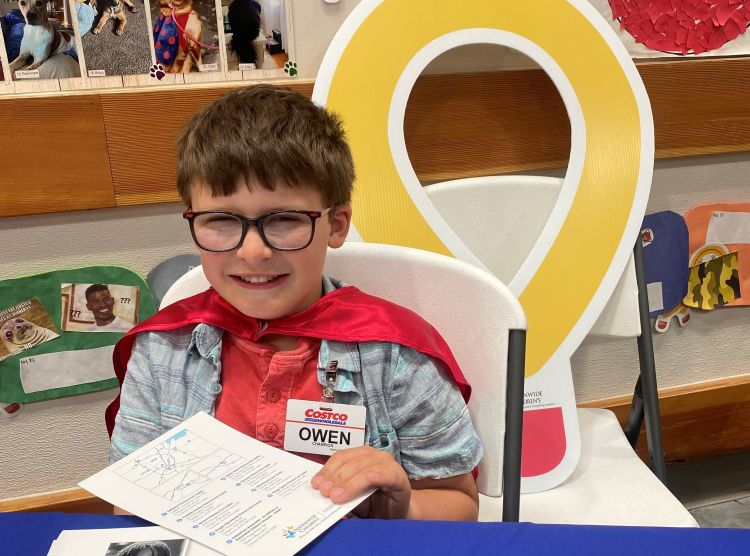 Owen sitting at a table with a Costco badge on