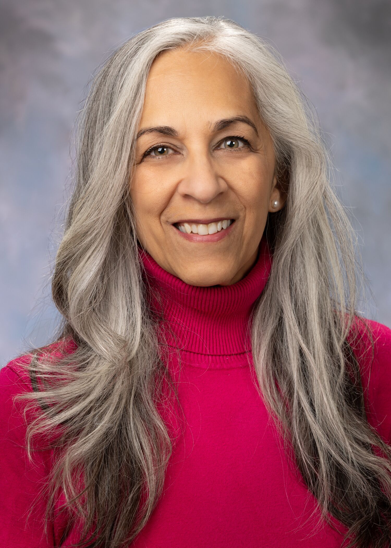Portrait of Ambre Emory-Maier. Ambre has long hair and is wearing a pink turtle-neck sweater. 