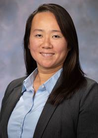 Portrait of Helen Wu. Helen is wearing a blue button up shirt and a black blazer.