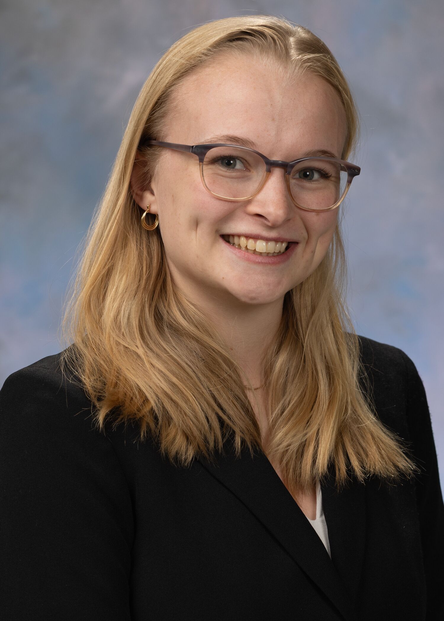 Portrait of Hollen Knoell. Hollen has blonde hair and glasses, and she is wearing a black top. 
