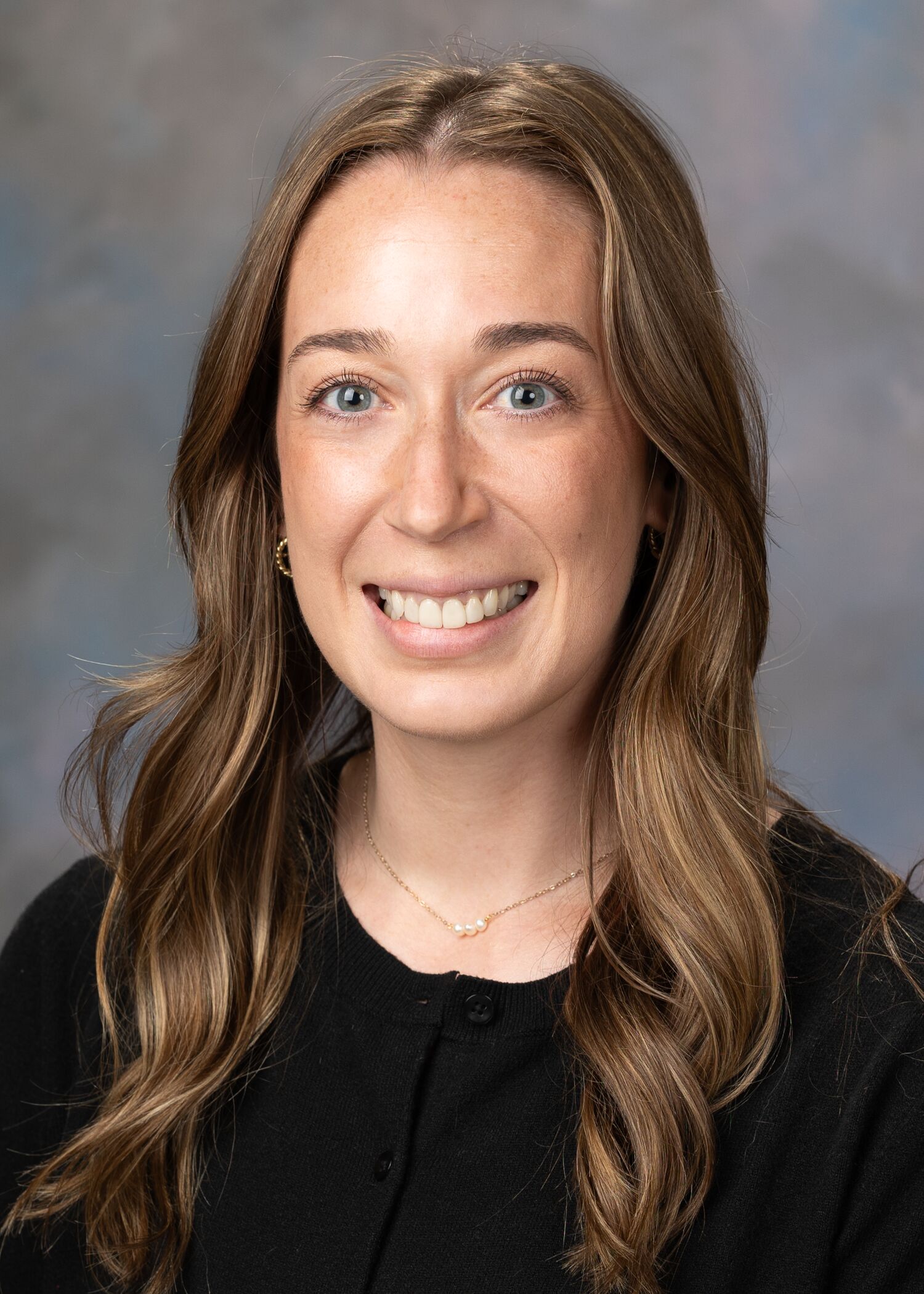 Portrait of Megan Stanley. Megan has long curled brown hair and is wearing a black top. 