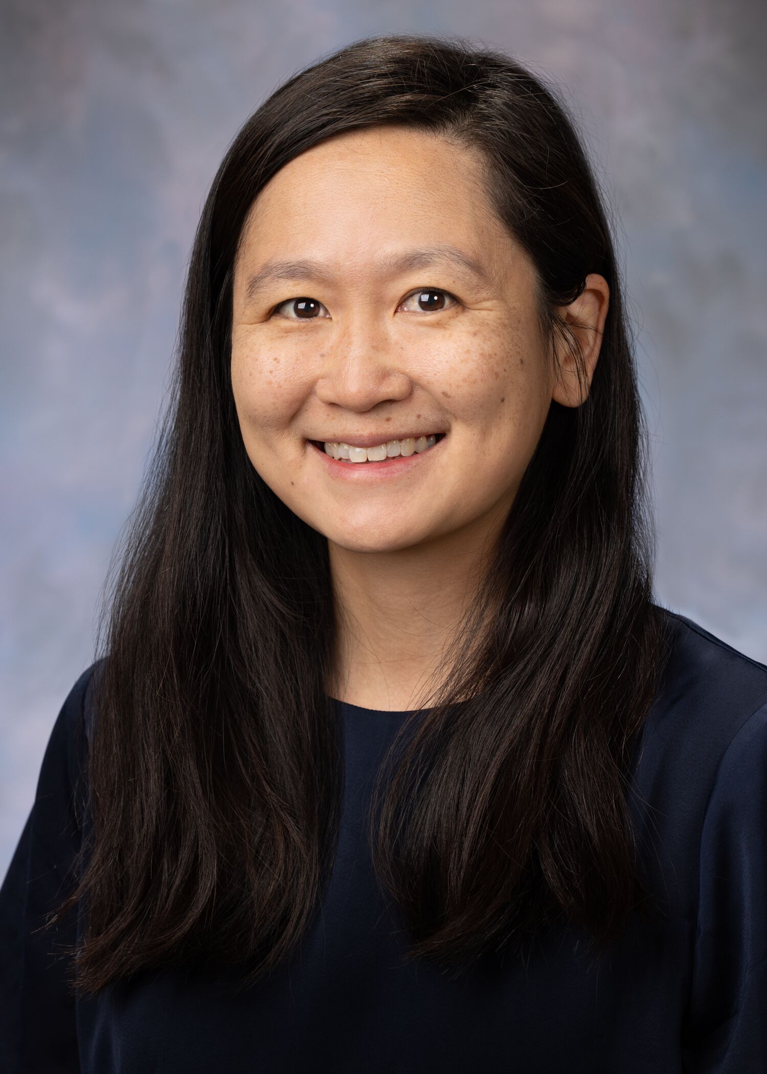 Portrait of Nina Mann. Nina is wearing a black shirt and her Nationwide Children's Hospital lab coat.
