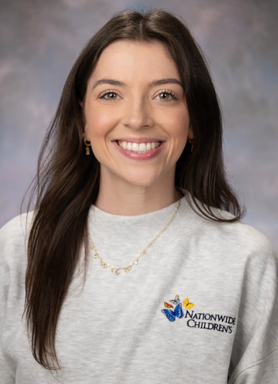 Portrait of Olivia Dieckmann, woman with long brown hair and a grey Nationwide Children's shirt.