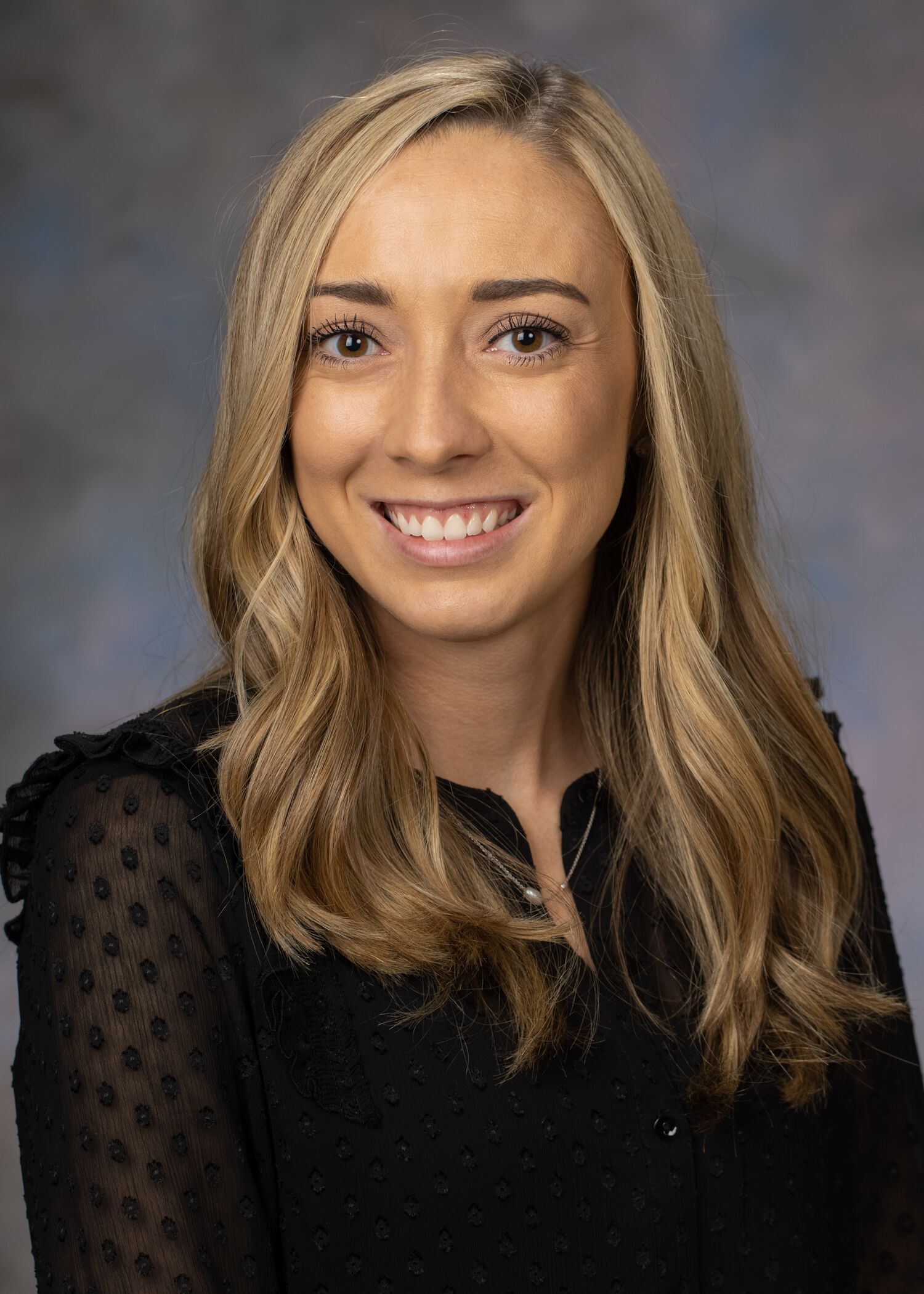 Portrait of Rachel Gaudio. Rachel has blonde hair and is wearing a black long-sleeved top. 