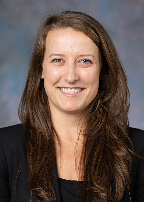 Portrait of Samantha Boch. Dr. Boch has long brown hair with a black top.